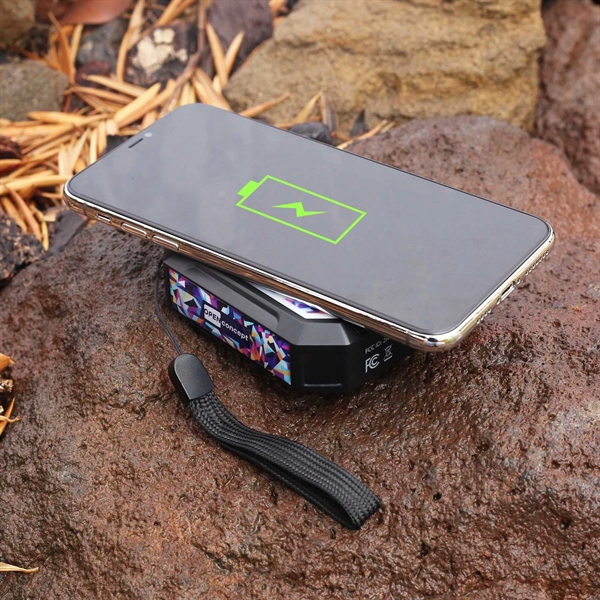 dark gray and multicolored Solr Powerbank on rock in the wilderness with phone charging on top